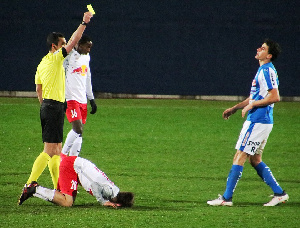Árbitro mostrando tarjeta amarilla en un partido de fútbol