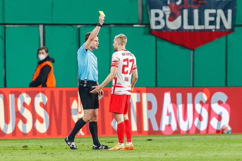 Árbitro mostrando tarjeta amarilla en partido mexicano